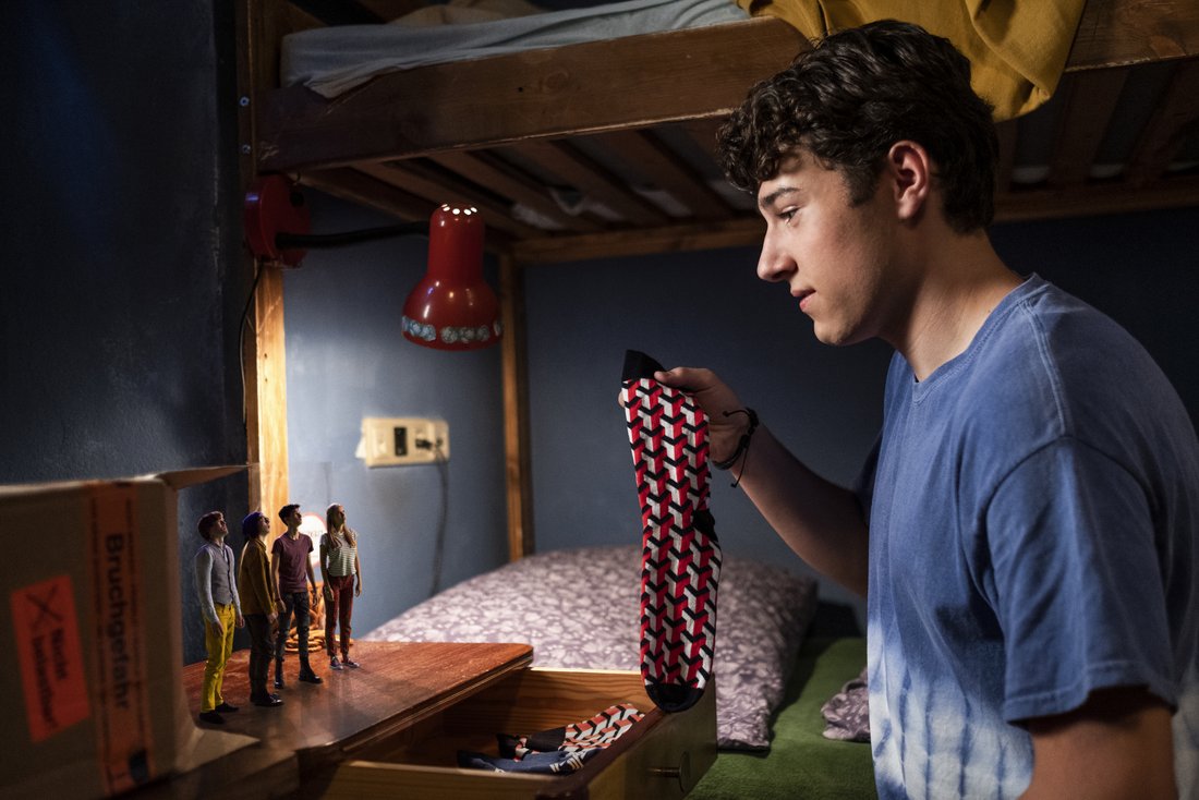 Help, I Shrunk My Friends - Still - A boy showing a sock to his shrunk friends who stand on top of a drawer near his bed.