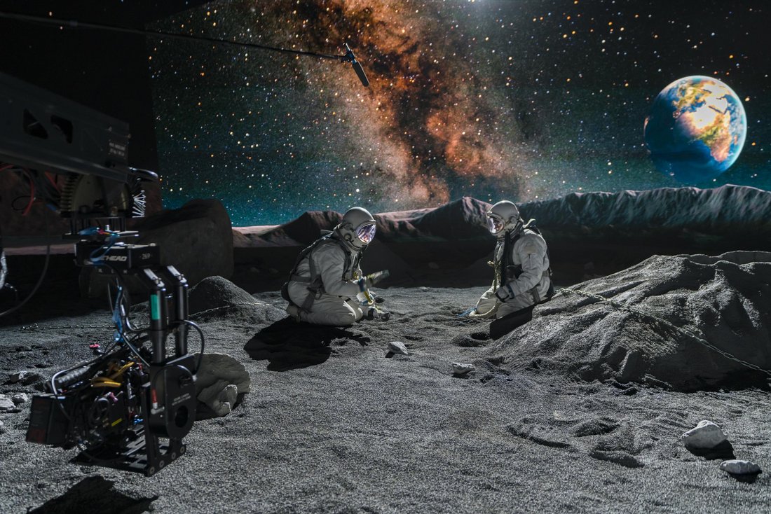 Two people in austronaut suits on the moon