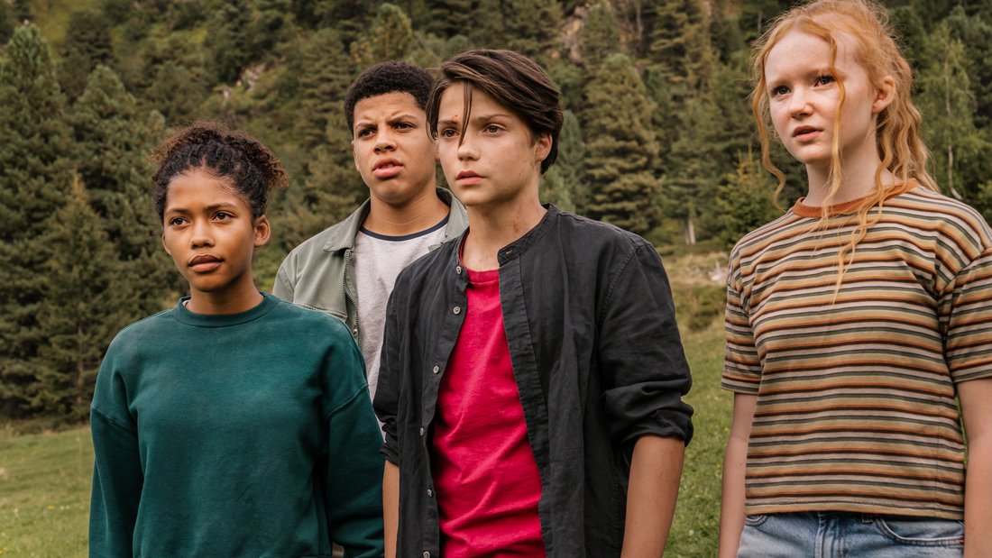 Woodwalkers - Still - A group of young friends in front of a forest staring at something offscreen.