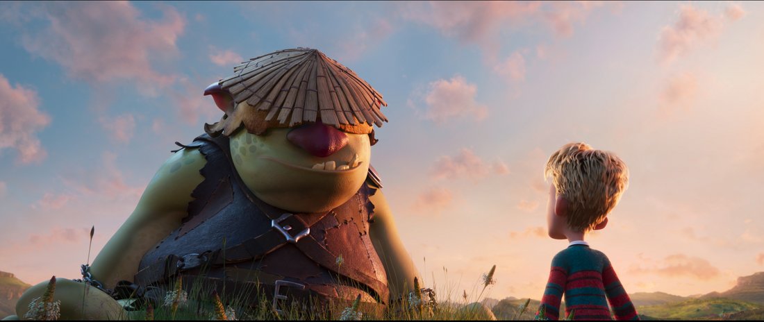 Still for Giants of La Mancha - a big green ogre with a straw hat on, standing in front of a young boy in a field.