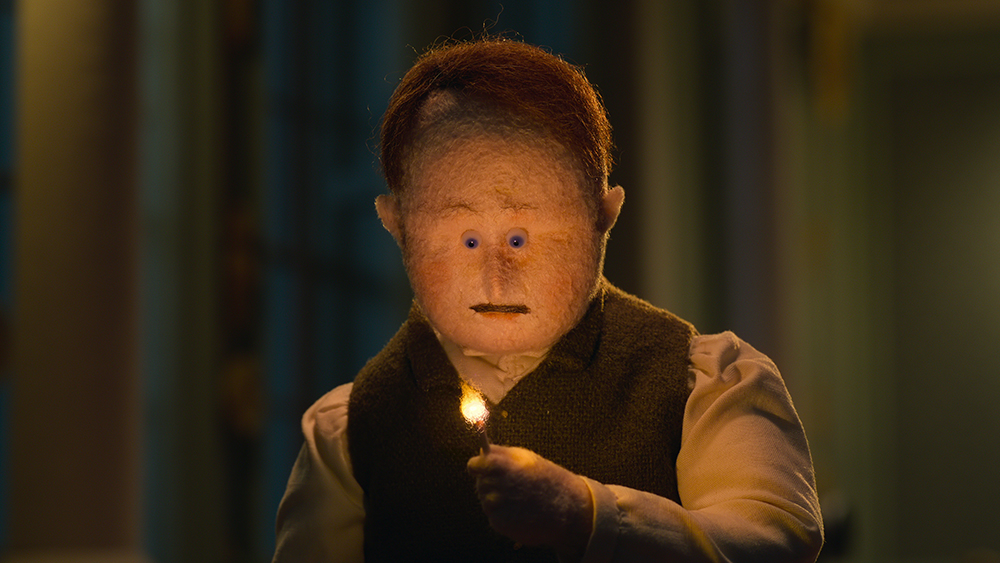 A man looking at a lighted match in his hand.